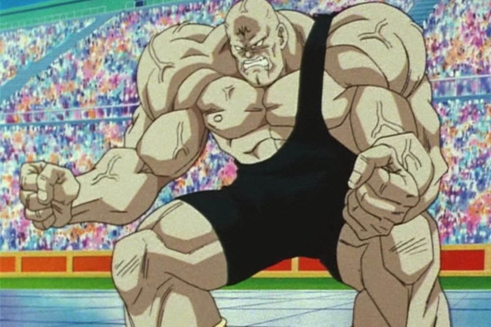Homme extrêmement musclé et chauve, vêtu d’un justaucorps noir, se tenant sur un ring de tournoi devant une foule en liesse.